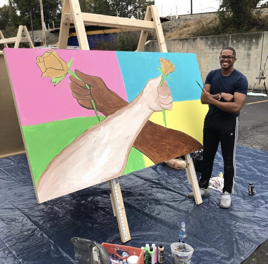 Photo: Artist Kenneth Brown beside his mural painting. Photo Courtesy of Uptown Greensboro on Instagram.