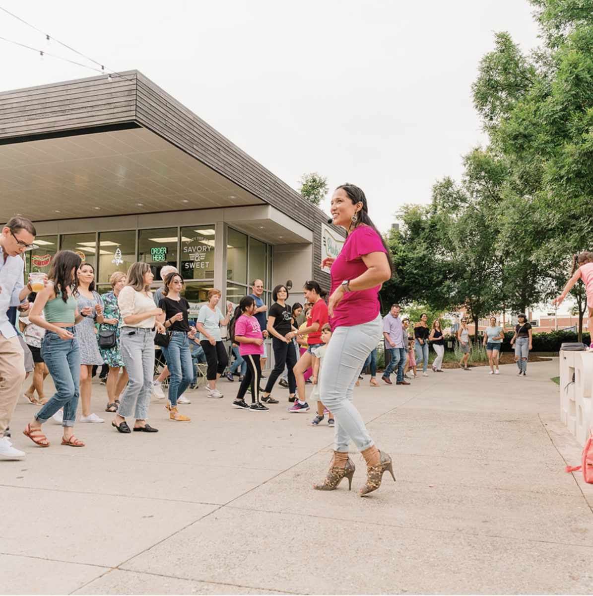 Noches Latinas Founder Maria Gonzalez instructing a dance lesson in the Market Square at Lebauer Park